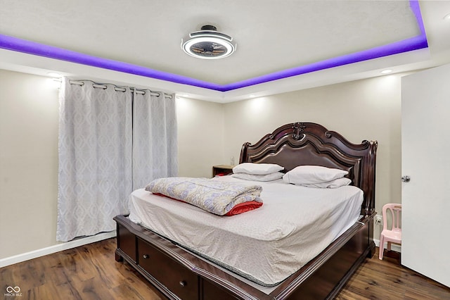 bedroom with dark hardwood / wood-style floors and a tray ceiling