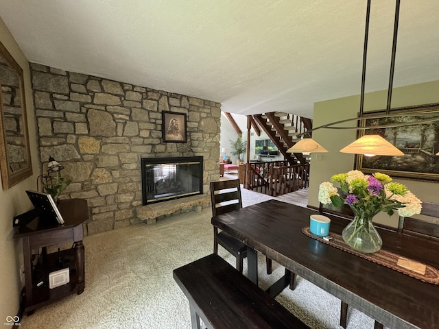 dining space featuring a fireplace, a textured ceiling, and carpet flooring