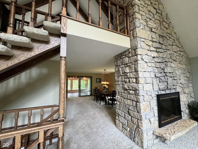 carpeted living room featuring high vaulted ceiling and a stone fireplace