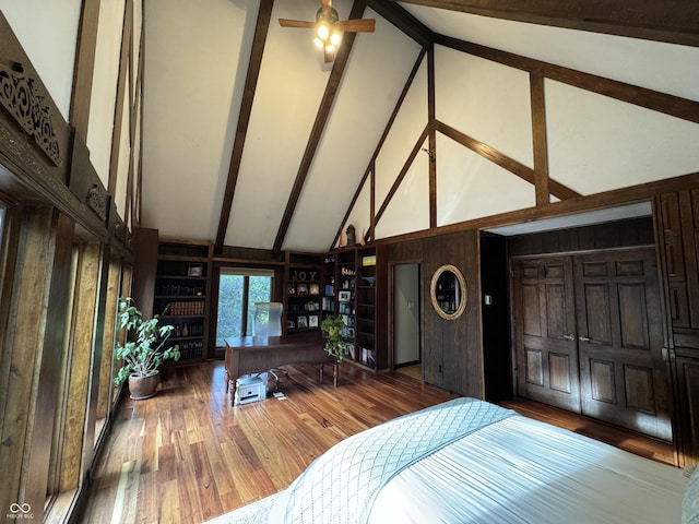 bedroom with beam ceiling, high vaulted ceiling, and hardwood / wood-style flooring