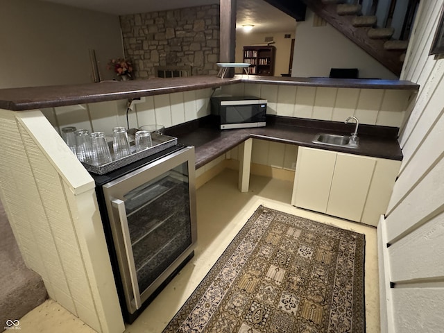 kitchen featuring a fireplace, wine cooler, tasteful backsplash, and sink