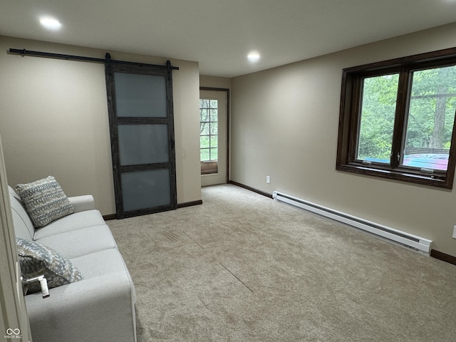 carpeted living room with a baseboard heating unit and a barn door