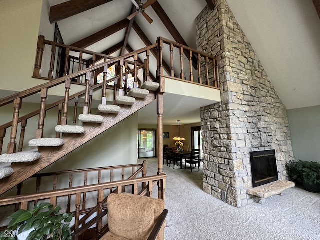 stairs with ceiling fan, high vaulted ceiling, a stone fireplace, and carpet