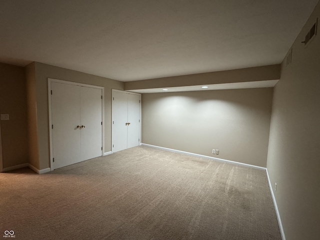 unfurnished bedroom with light colored carpet and multiple closets