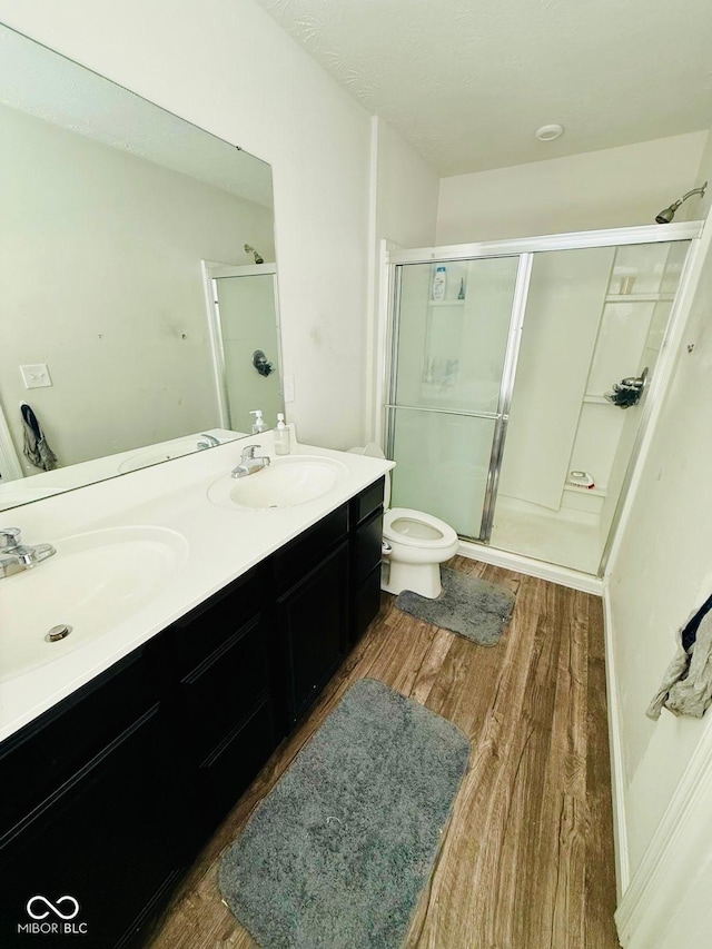 bathroom featuring hardwood / wood-style floors, an enclosed shower, vanity, and toilet