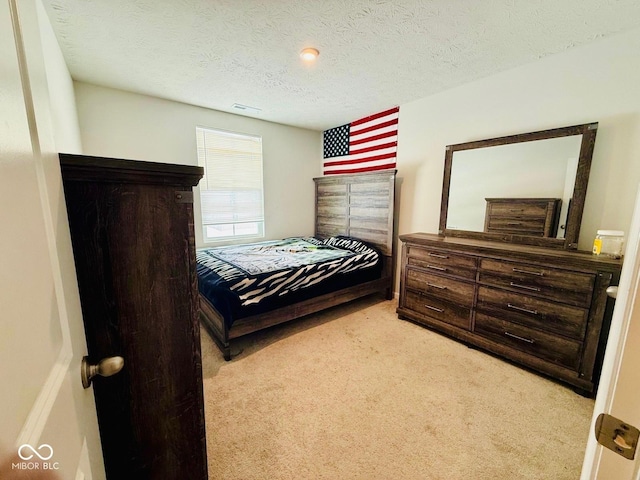 bedroom with a textured ceiling and light colored carpet