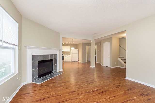 unfurnished living room with wood-type flooring, a textured ceiling, and a fireplace