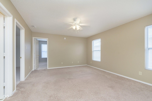 unfurnished room featuring ceiling fan, light colored carpet, and a textured ceiling