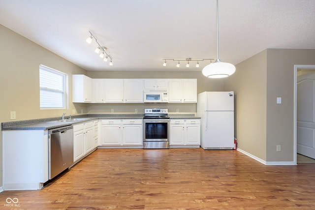 kitchen featuring sink, white cabinetry, hanging light fixtures, light wood-type flooring, and stainless steel appliances