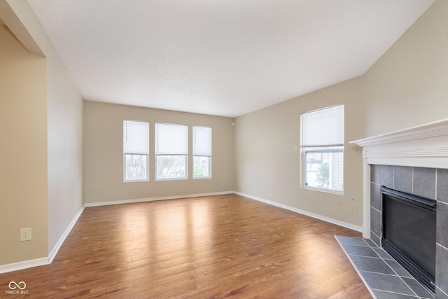 unfurnished living room with a tiled fireplace and dark wood-type flooring