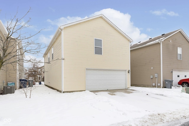 view of snow covered exterior with a garage and central AC