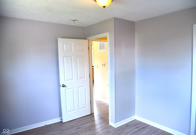 empty room with a textured ceiling and hardwood / wood-style flooring