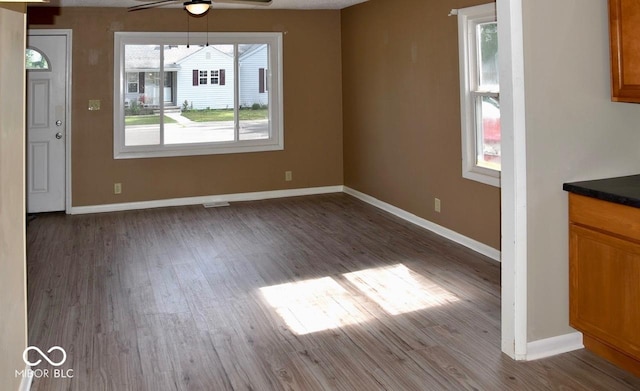 unfurnished dining area featuring ceiling fan and dark hardwood / wood-style floors