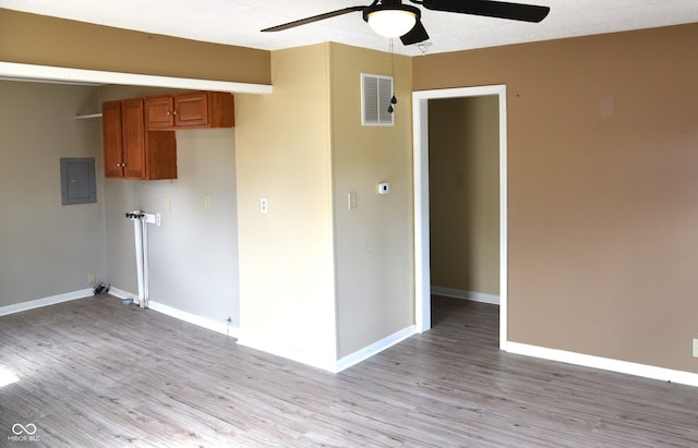 spare room with ceiling fan, electric panel, and light hardwood / wood-style flooring