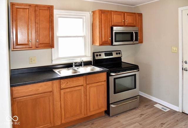 kitchen featuring sink, crown molding, stainless steel appliances, and light hardwood / wood-style floors