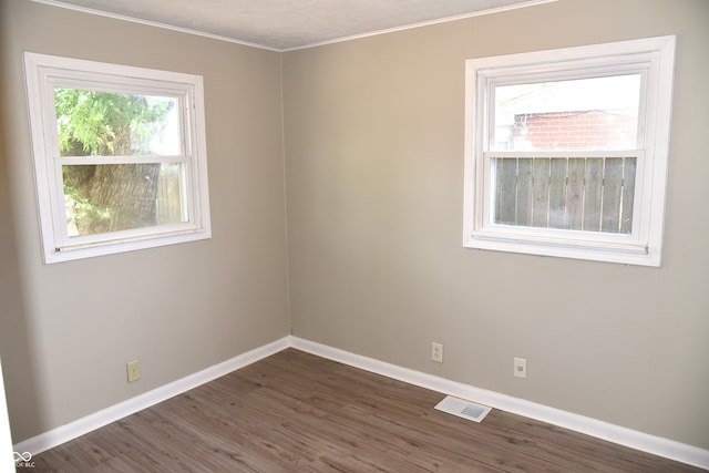 empty room with dark hardwood / wood-style flooring and ornamental molding