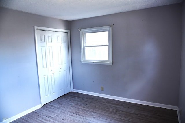 unfurnished bedroom with dark wood-type flooring and a closet