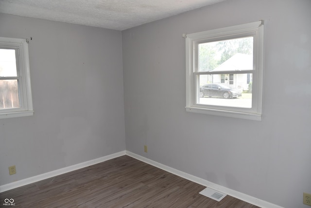 empty room featuring a textured ceiling and dark hardwood / wood-style floors