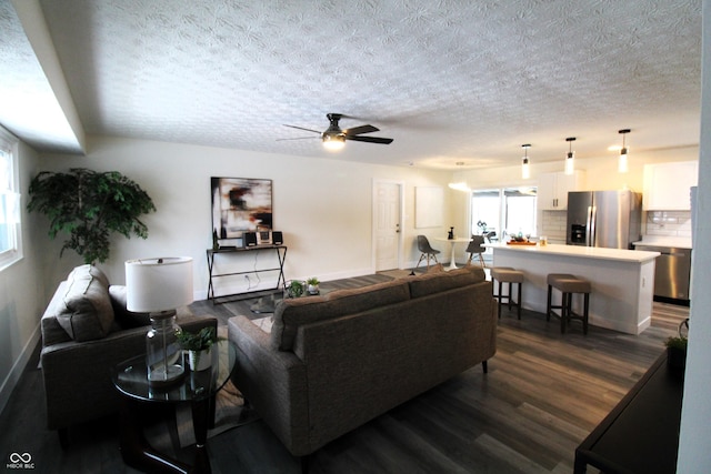 living room featuring dark wood-type flooring, ceiling fan, and a textured ceiling