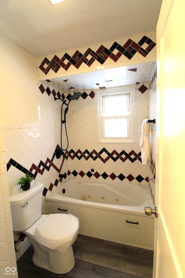 bathroom featuring toilet, wood-type flooring, tile walls, a textured ceiling, and tiled shower / bath combo