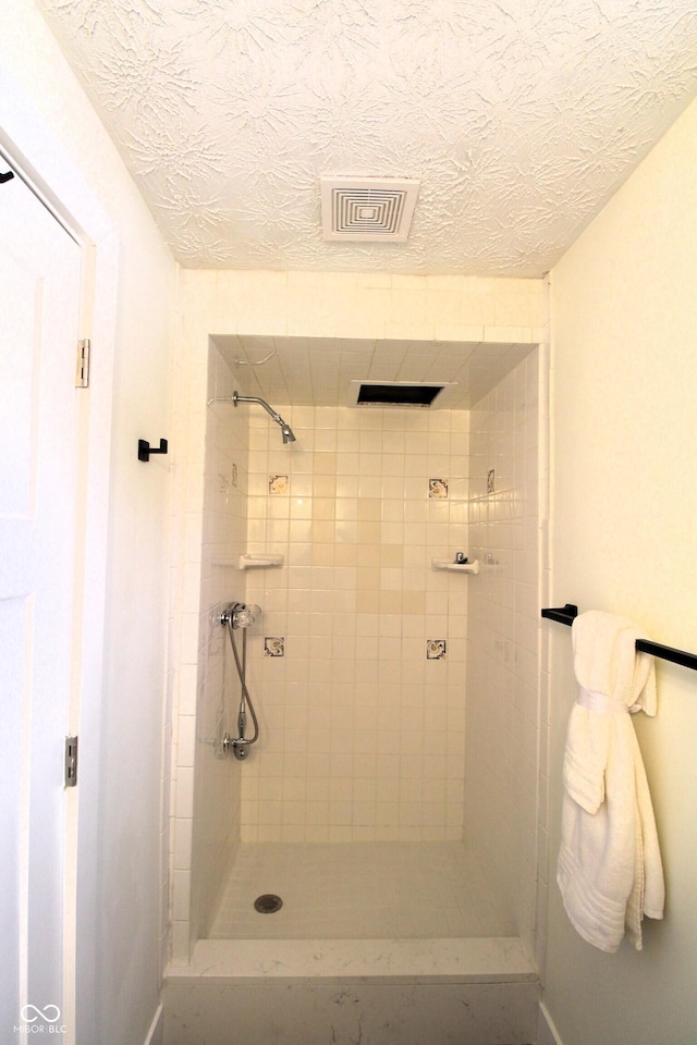 bathroom featuring a tile shower and a textured ceiling