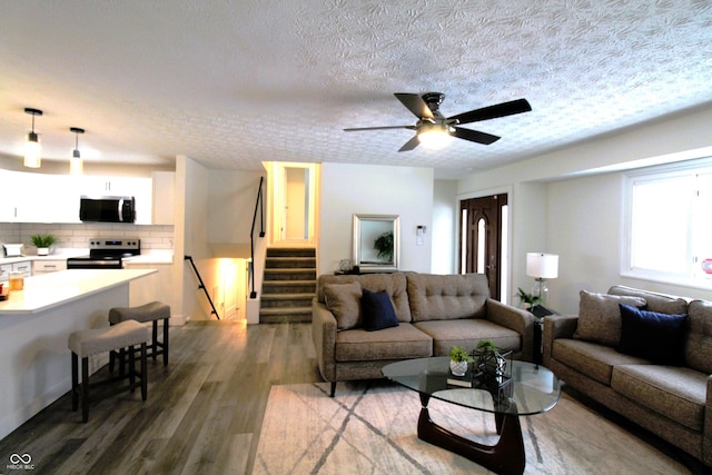 living room featuring dark hardwood / wood-style flooring, a textured ceiling, and ceiling fan