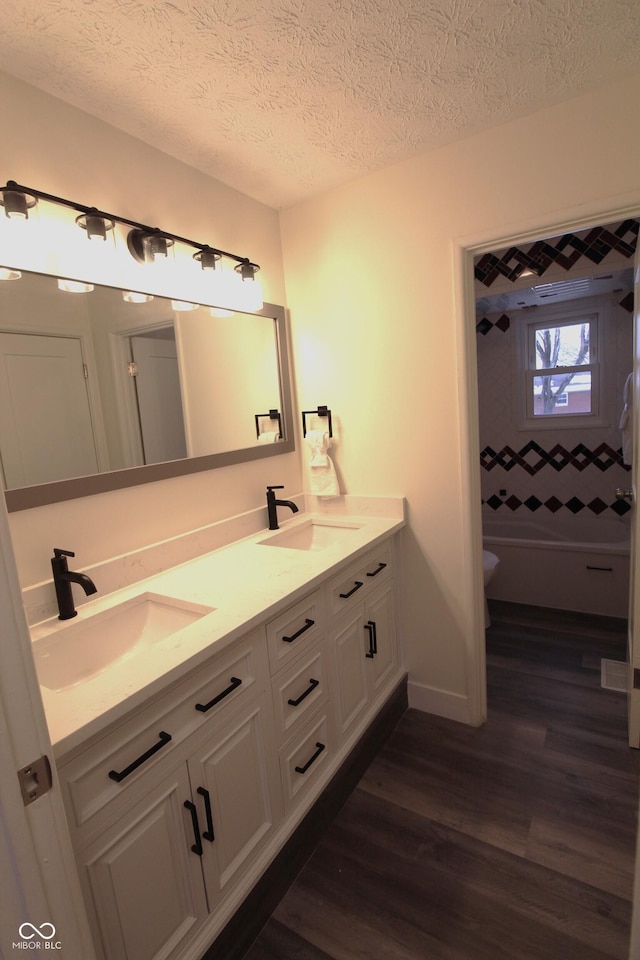 bathroom featuring hardwood / wood-style flooring, vanity, a textured ceiling, and toilet