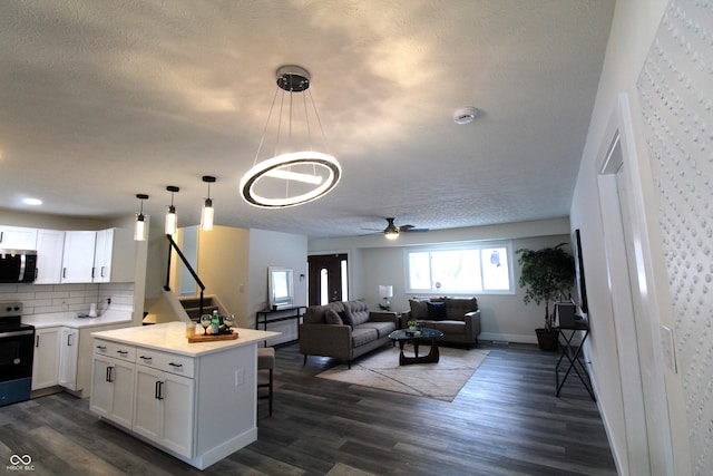 kitchen with pendant lighting, dark hardwood / wood-style flooring, range with electric cooktop, and white cabinets