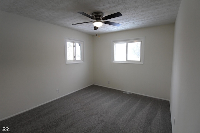 unfurnished room featuring ceiling fan, a textured ceiling, and dark colored carpet