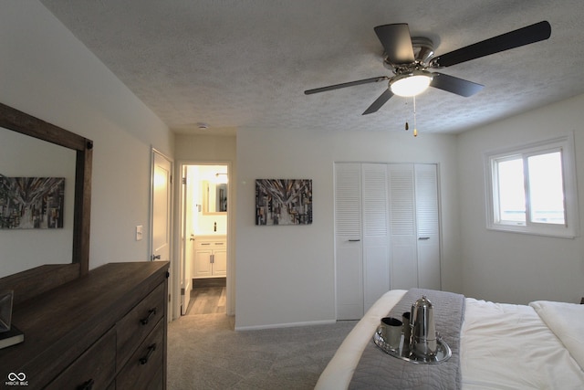 carpeted bedroom featuring ceiling fan, ensuite bath, a textured ceiling, and a closet