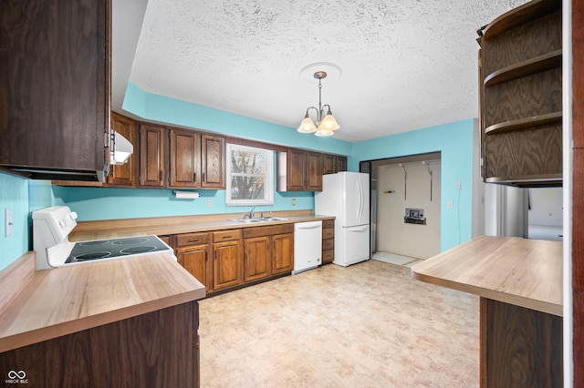 kitchen with an inviting chandelier, decorative light fixtures, white appliances, range hood, and sink