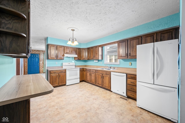 kitchen featuring decorative light fixtures, a notable chandelier, sink, white appliances, and a textured ceiling