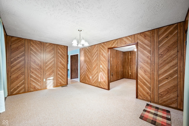 basement featuring a notable chandelier, wooden walls, and a textured ceiling