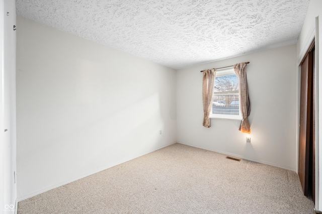 unfurnished bedroom featuring light carpet, a closet, and a textured ceiling