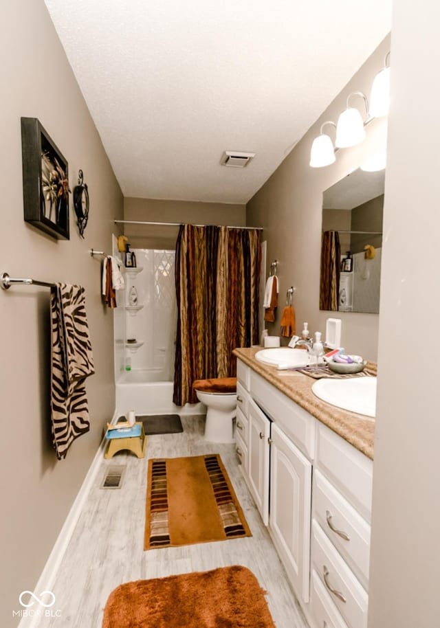 bathroom featuring toilet, hardwood / wood-style flooring, a shower with shower curtain, a textured ceiling, and vanity