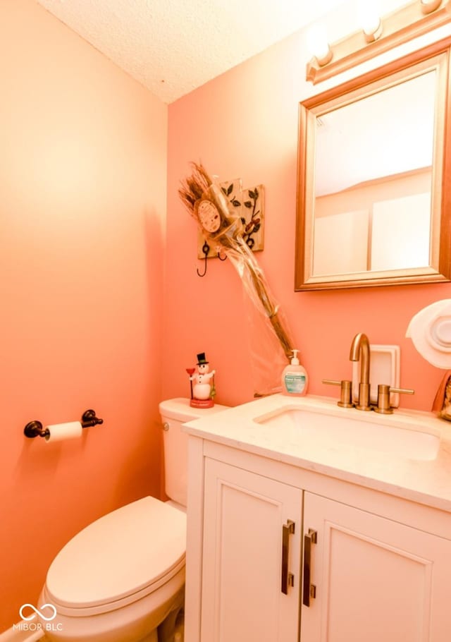 bathroom featuring a textured ceiling, toilet, and vanity