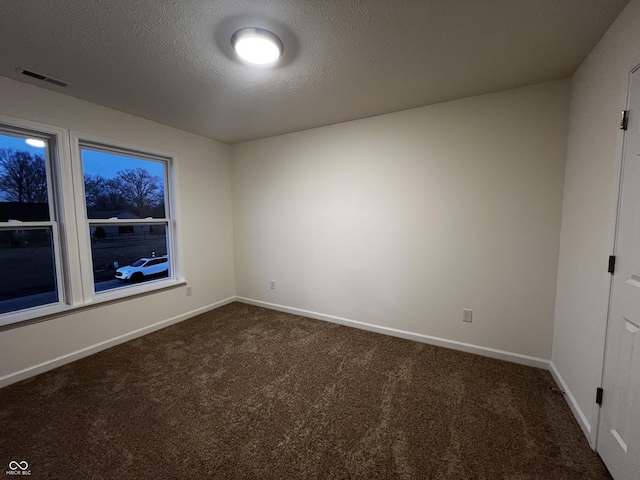 unfurnished room featuring baseboards, visible vents, dark colored carpet, and a textured ceiling