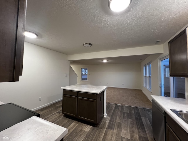 kitchen with dark wood-style floors, light countertops, stainless steel dishwasher, and open floor plan