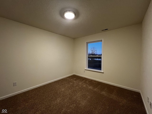 unfurnished room featuring baseboards, visible vents, dark carpet, and a textured ceiling