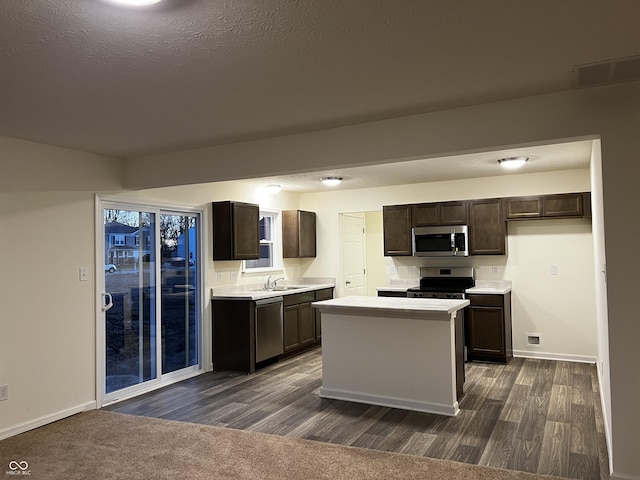 kitchen featuring a kitchen island, a sink, light countertops, appliances with stainless steel finishes, and dark brown cabinets