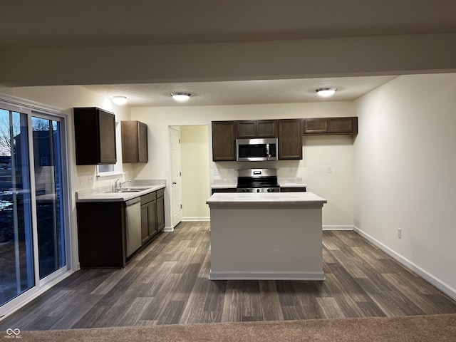 kitchen featuring dark wood-style floors, light countertops, appliances with stainless steel finishes, and a sink