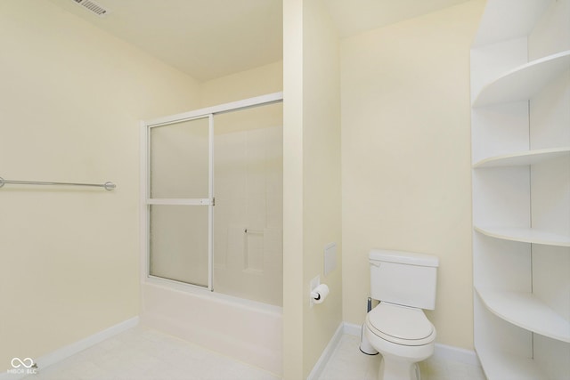 bathroom featuring toilet and bath / shower combo with glass door