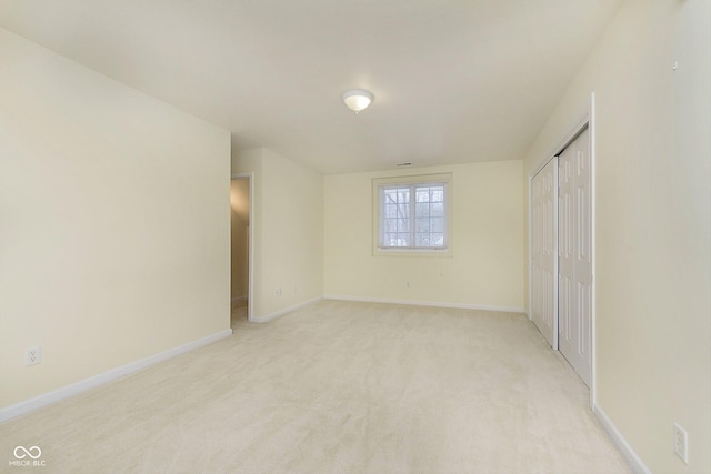 unfurnished bedroom featuring light carpet and a closet