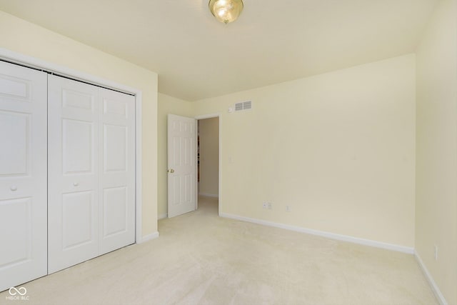 unfurnished bedroom featuring light carpet and a closet