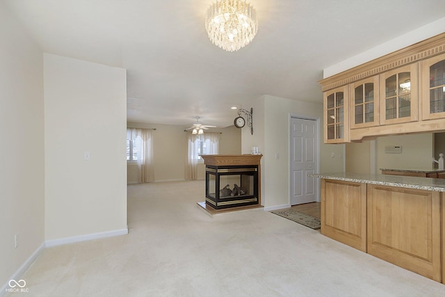 kitchen featuring light carpet, light brown cabinets, light stone countertops, and a multi sided fireplace