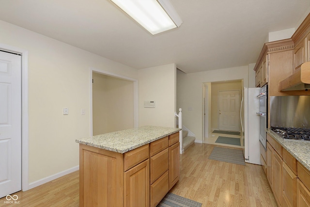 kitchen with light stone countertops, light hardwood / wood-style flooring, stainless steel gas cooktop, and a kitchen island