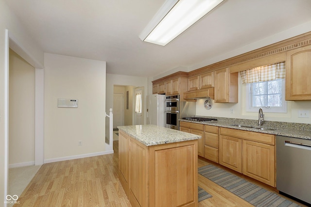 kitchen featuring light hardwood / wood-style floors, a center island, sink, appliances with stainless steel finishes, and light stone counters