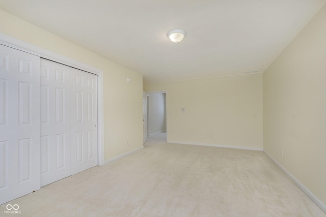 unfurnished bedroom featuring light carpet and a closet