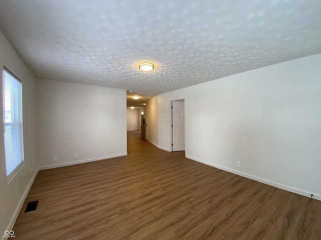 spare room featuring dark wood-type flooring and a textured ceiling