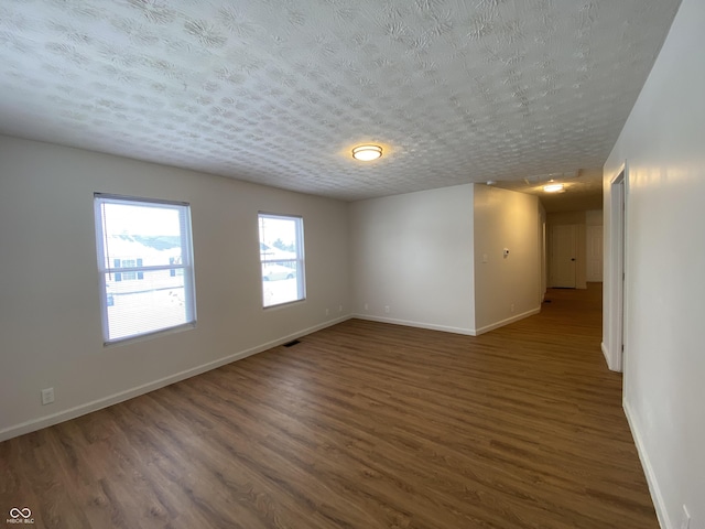 spare room featuring a textured ceiling and dark hardwood / wood-style floors